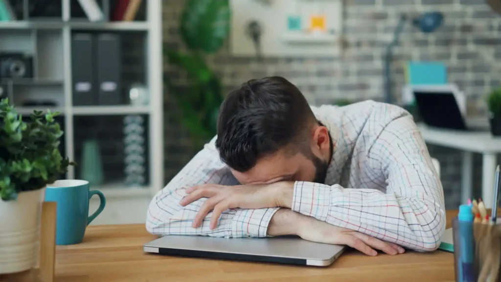 Tired man resting his head on his desk, a common sign of low testosterone